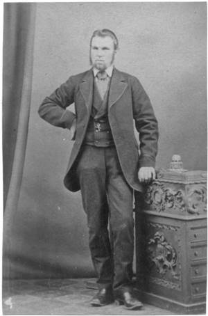 A person in a suit standing next to a chest

Description automatically generated
